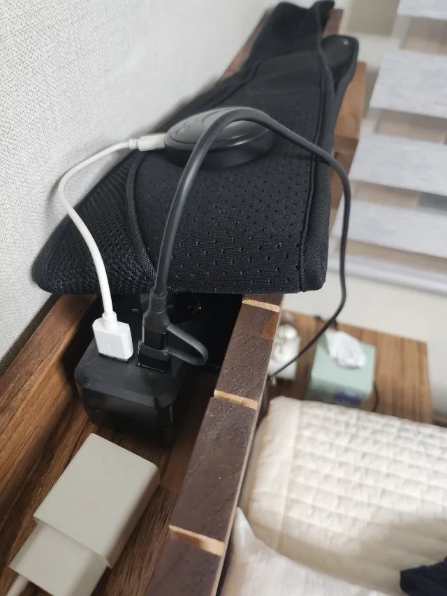 침대 가구 뒤 좁은 공간에 모여 있는 충전기와 전원 케이블