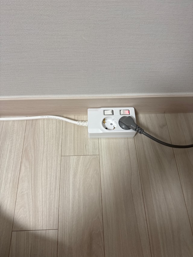 걸레받이 앞 2구 멀티탭에 연결된 검은 전원선과 흰색 공급 전선