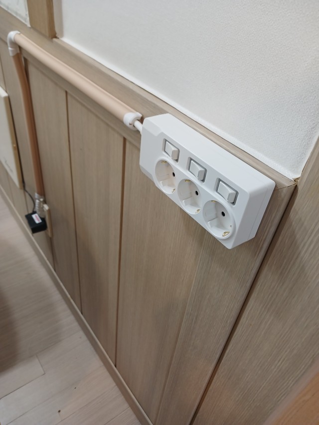 목재 벽면에 자리 잡은 써보니 3구 멀티탭과 정리된 전선