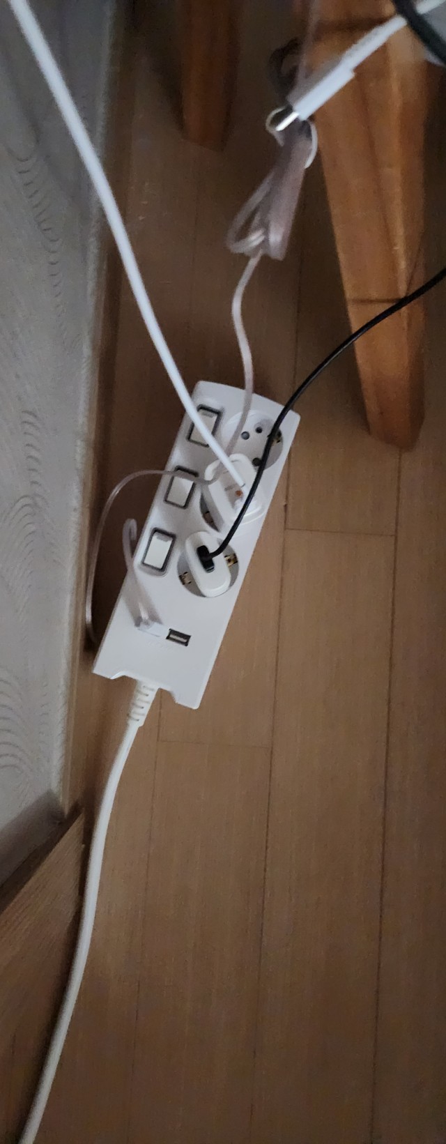 나무 가구 옆 USB 포트와 개별 스위치가 있는 멀티탭의 플러그와 케이블